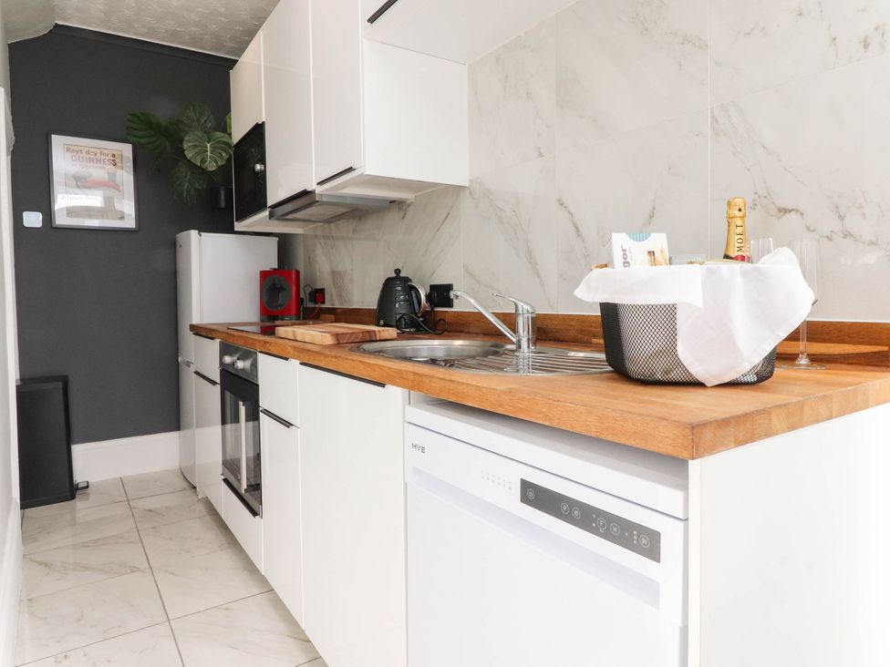 A kitchen with a sink, dishwasher, and fridge at 4 Green Street in Keighley
