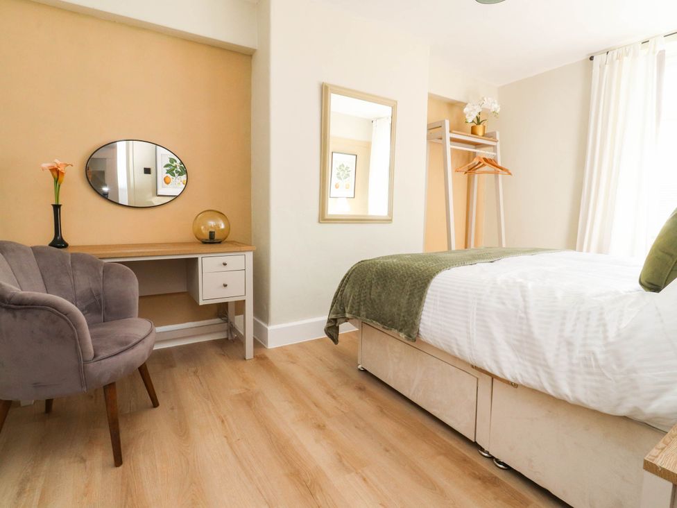 A bedroom with a bed, desk, chair and mirror at 4 Green Street in Keighley