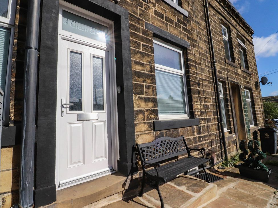 An outdoor view of the entrance with a door and a bench at 4 Green Street Keighley