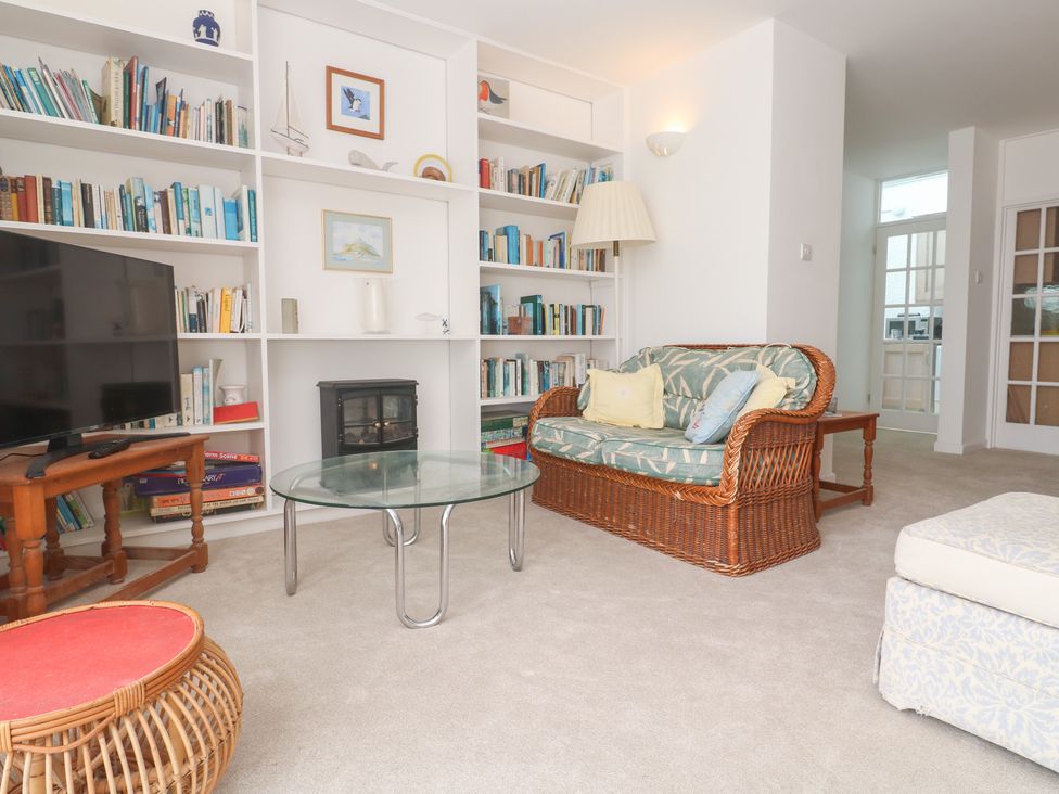 A living room with a television, bookshelf, and sofa at Flat 2, Moonrakers in St. Ives