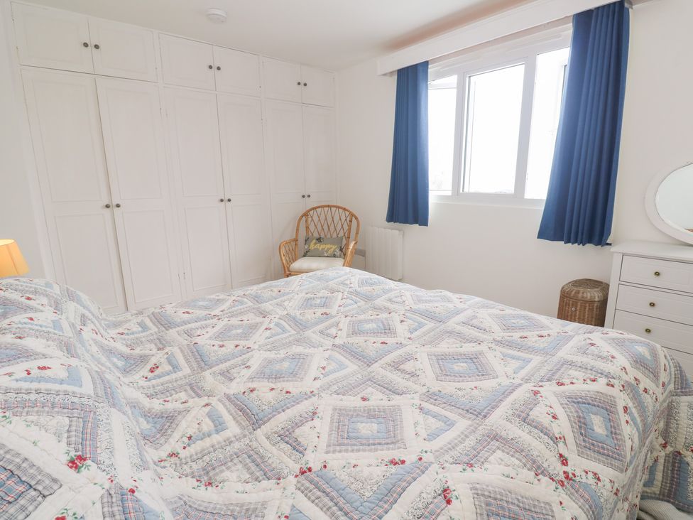 A bedroom with a bed and wardrobes at Flat 2, Moonrakers in St. Ives