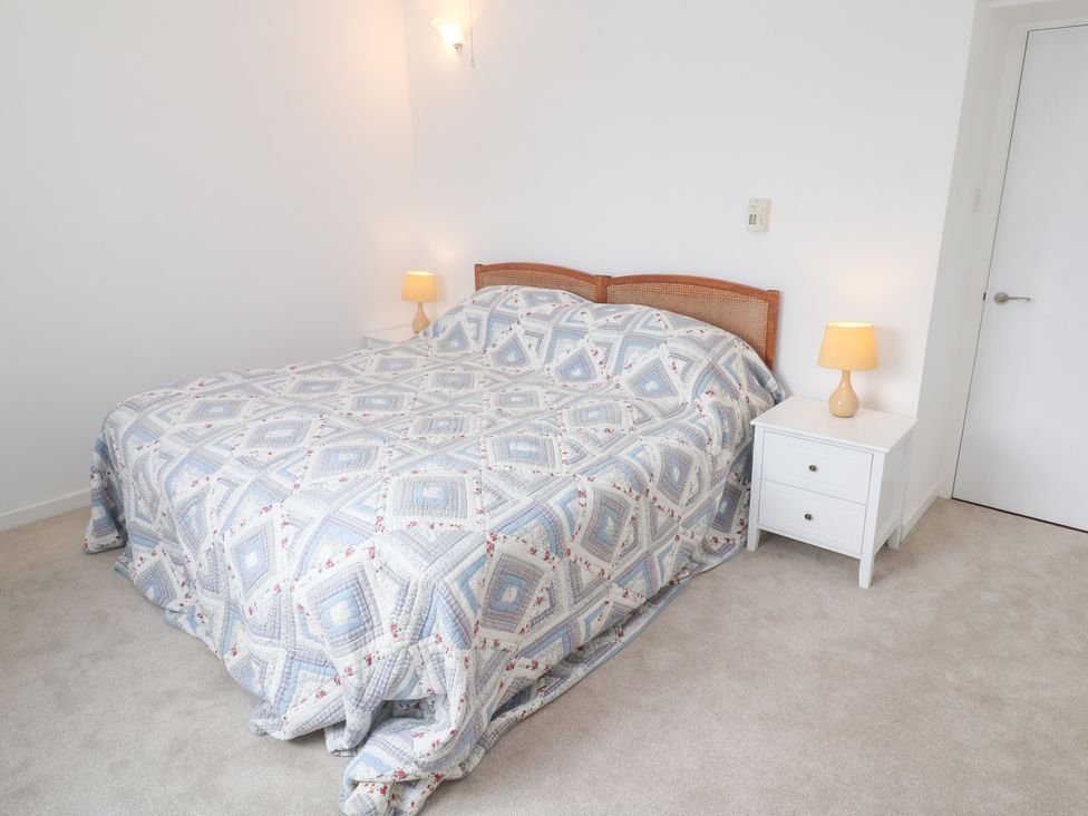 A bedroom with a bed and nightstands at Flat 2, Moonrakers in St. Ives