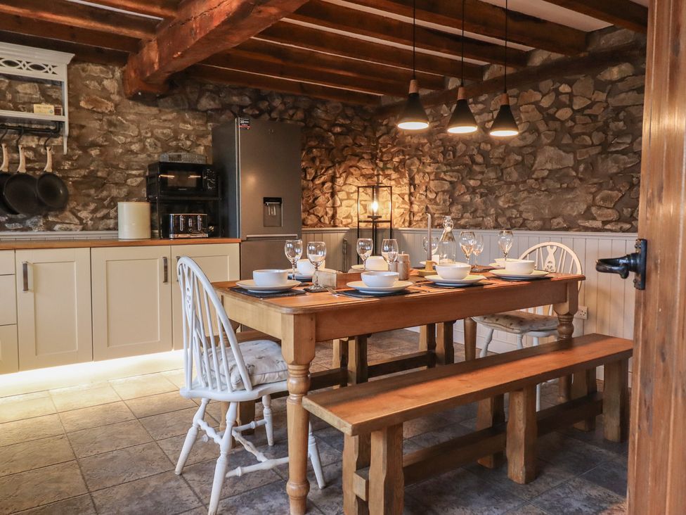 A kitchen with a dining area and stone walls at The Granary in Welshpool