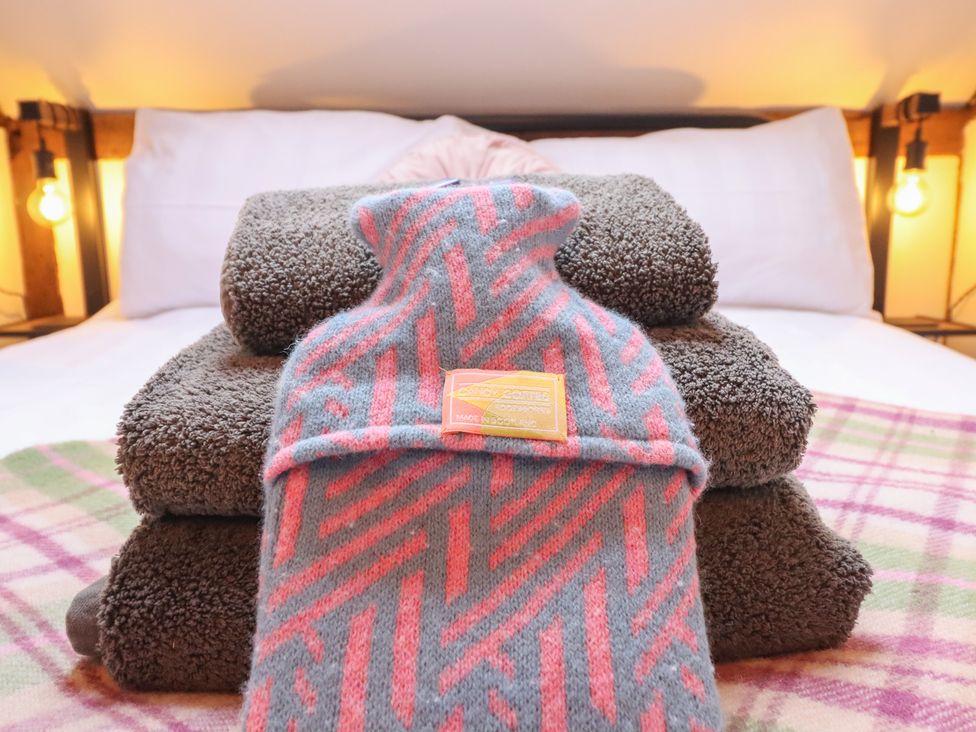 Towels and a hot water bottle on a bed at The Granary in Welshpool