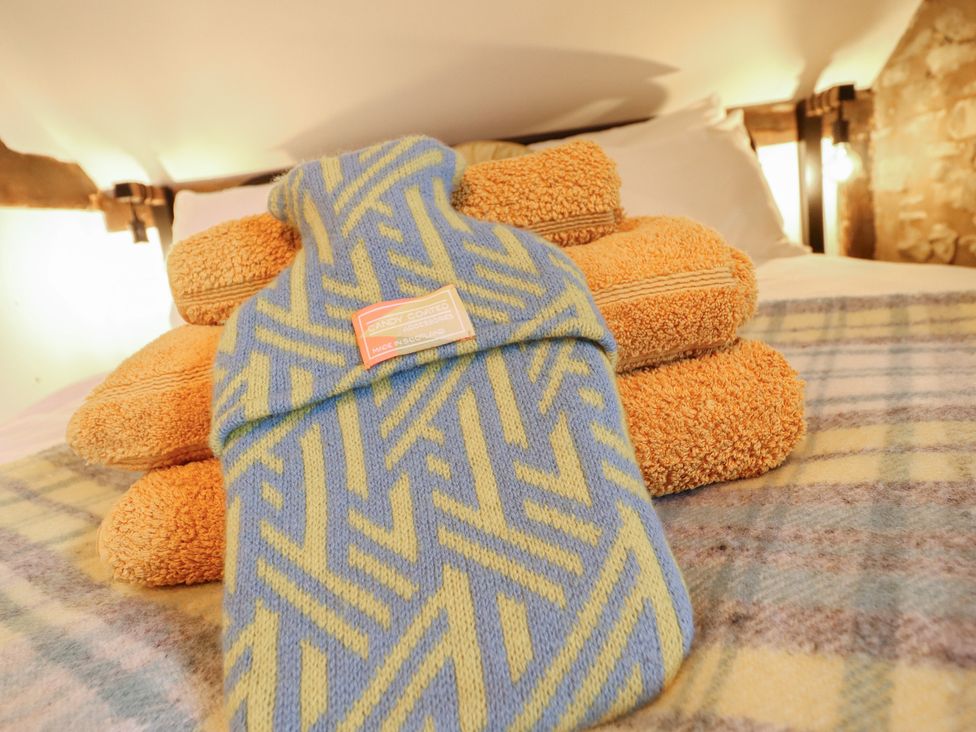 A hot water bottle and stacked towels on a bed at The Granary in Welshpool