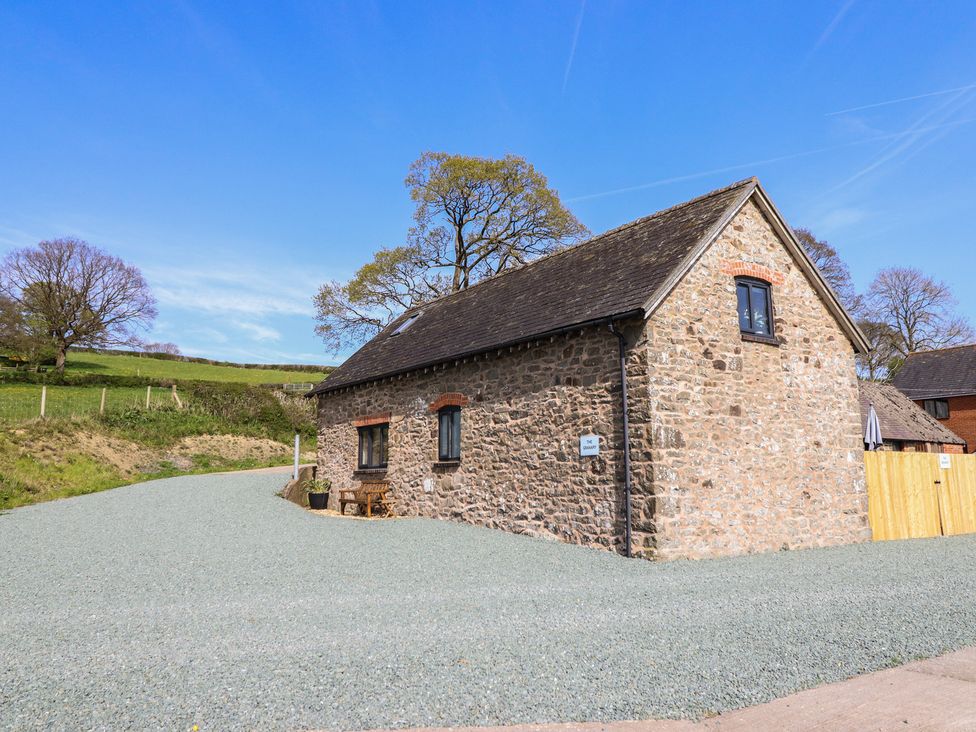 A stone building with gravel driveway at The Granary in Llangyniew near Llanfair Caereinion