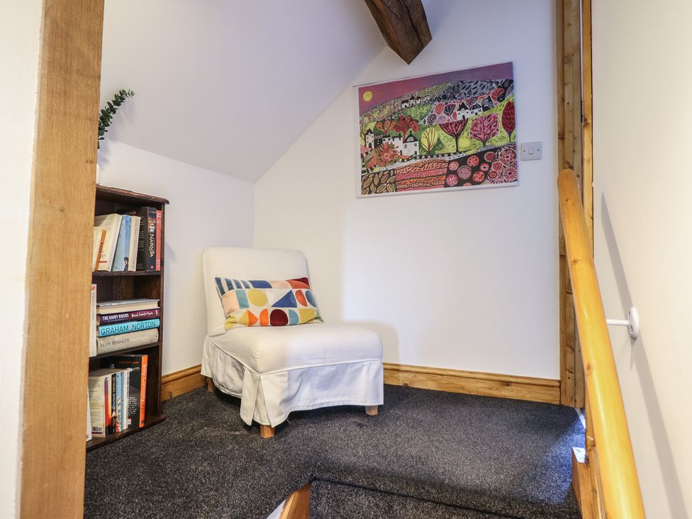A landing area with a chair and a bookshelf at The Granary in Llangyniew near Llanfair Caereinion