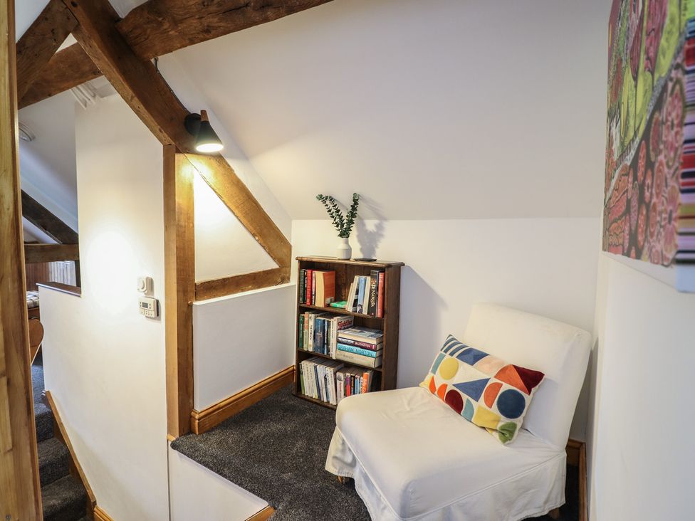 A landing area with a chair and bookshelf at The Granary in Llangyniew near Llanfair Caereinion
