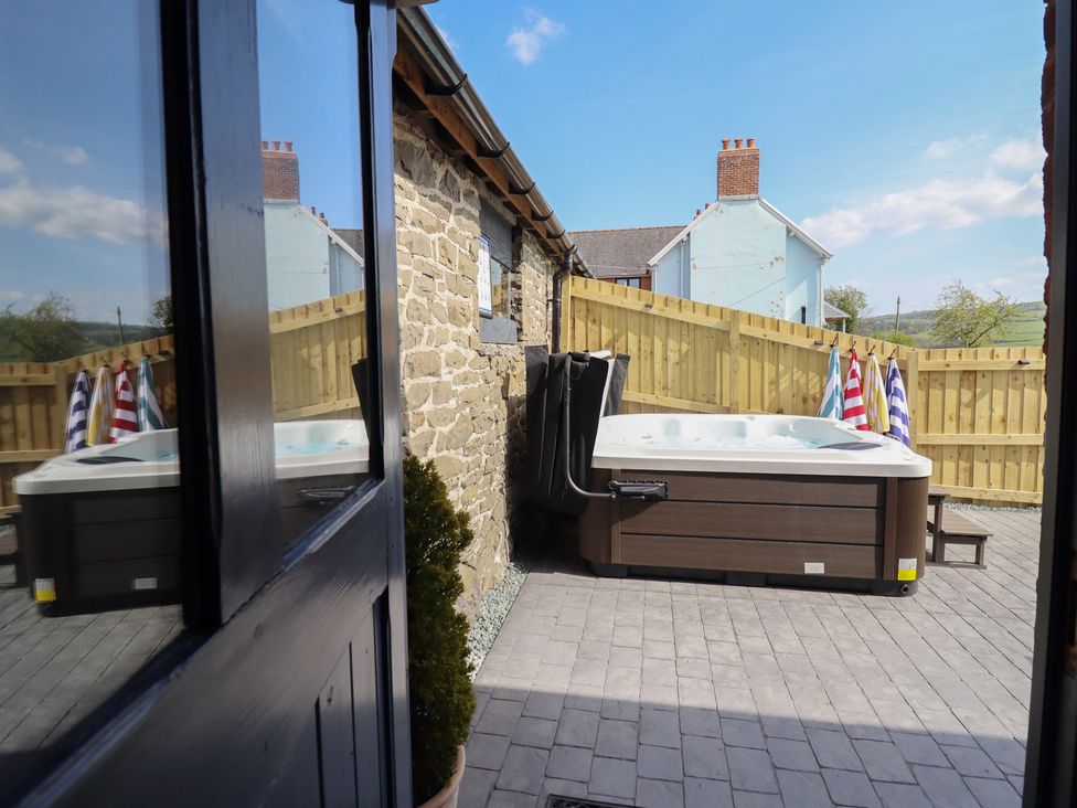 A garden with a hot tub and towels hanging near a wooden fence at The Granary in Llangyniew near Llanfair Caereinion