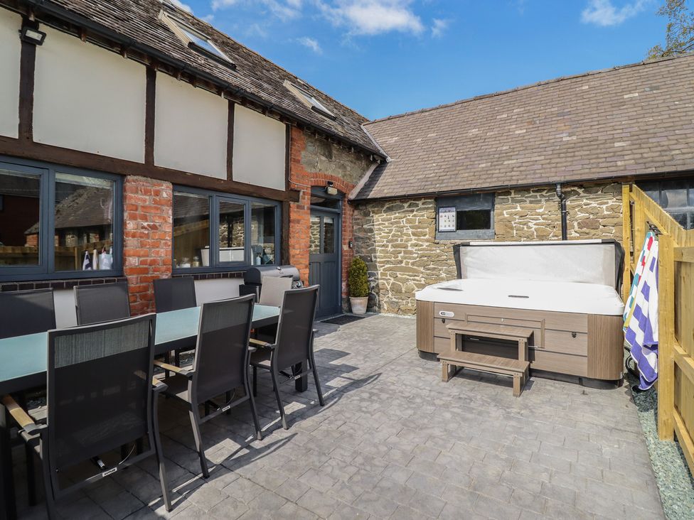 An outdoor area with a dining table and hot tub at The Granary in Llangyniew near Llanfair Caereinion