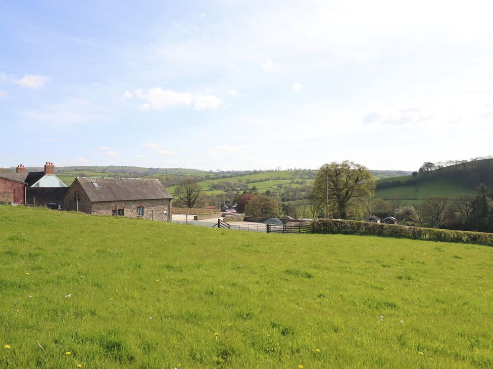 A countryside view with houses and fields at The Granary Llangyniew near Llanfair Caereinion