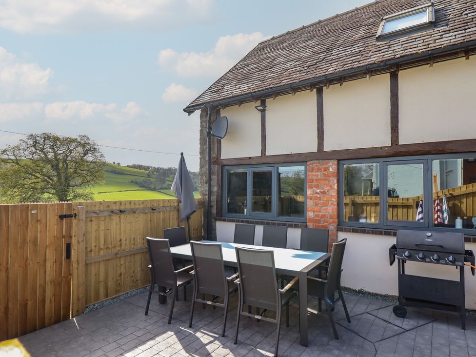 An outdoor dining area with a table and chairs at The Granary in Llangyniew near Llanfair Caereinion