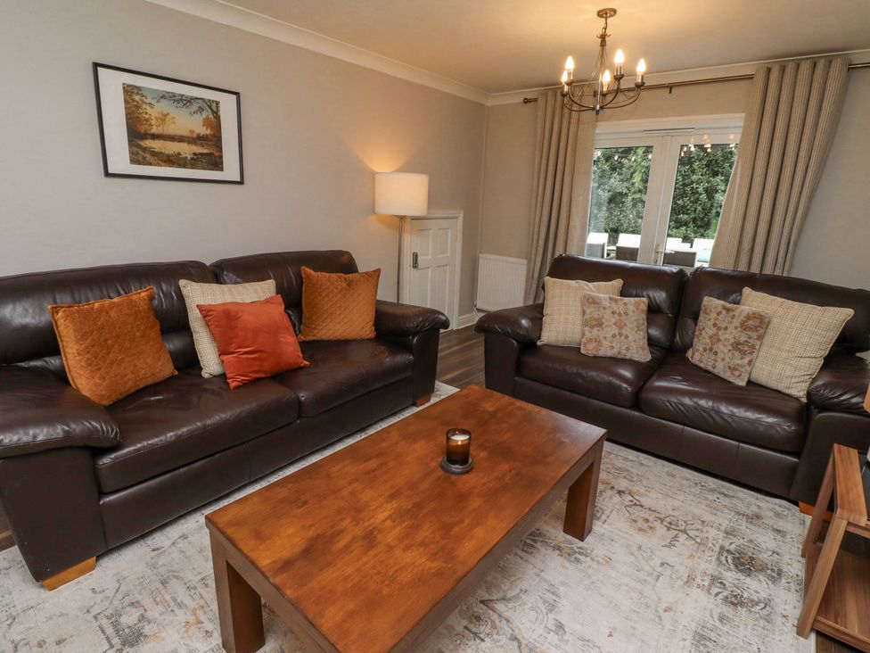 A living room with two brown leather sofas a wooden coffee table and a floor lamp at Sparrow House in Alnwick