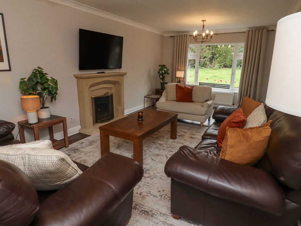 A living room with leather and fabric sofas a wooden coffee table fireplace and a window at Sparrow House in Alnwick