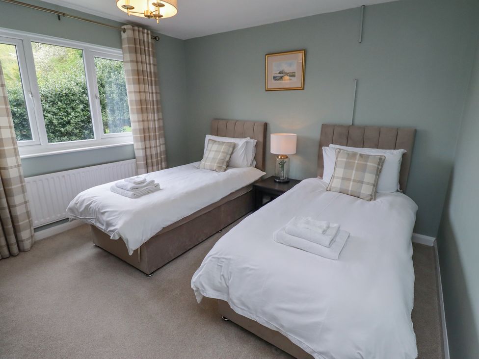 A bedroom with two single beds each with a pillow and folded towels a lamp on a nightstand and a window with curtains at Sparrow House in Alnwick