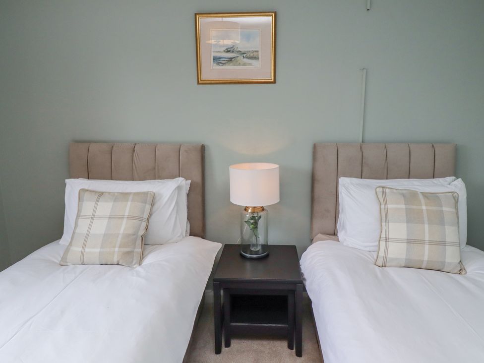 A bedroom with two single beds a nightstand with a lamp and a framed picture on the wall at Sparrow House in Alnwick