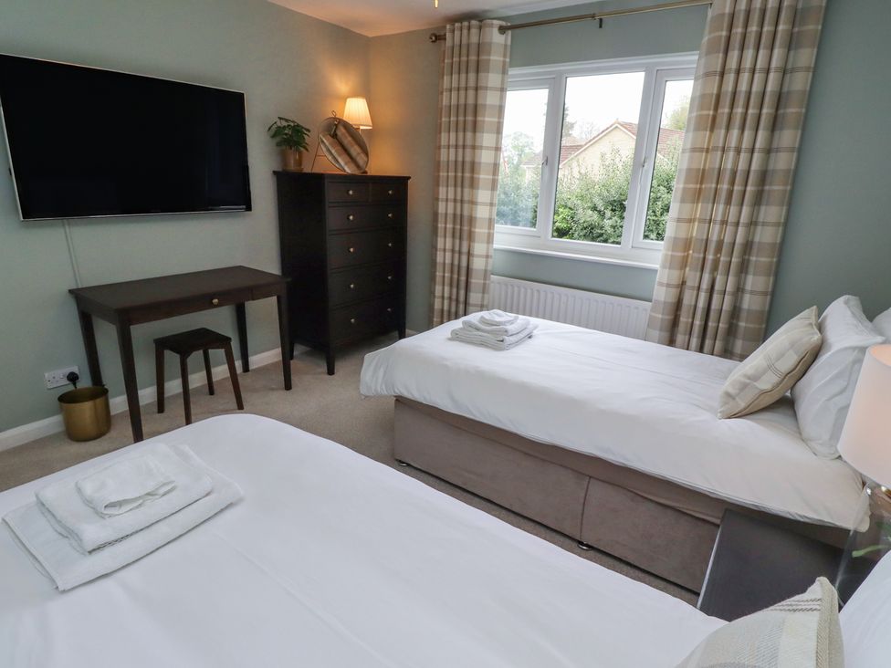 A bedroom with two single beds a desk a chest of drawers and a wall mounted television at Sparrow House in Alnwick