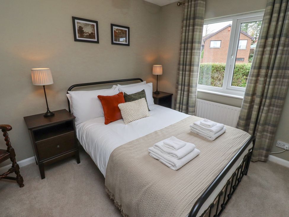 A bedroom with a bed with towels on it two bedside tables with lamps and a window with curtains at Sparrow House in Alnwick
