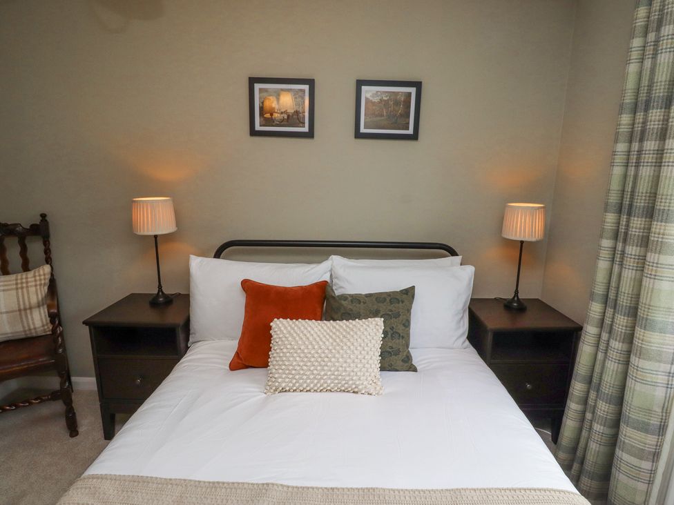 A bedroom with a bed with three pillows two lamps on bedside tables and two pictures on the wall at Sparrow House in Alnwick