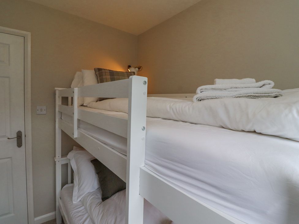 A bedroom with a white bunk bed and folded towels on the top bunk at Sparrow House in Alnwick