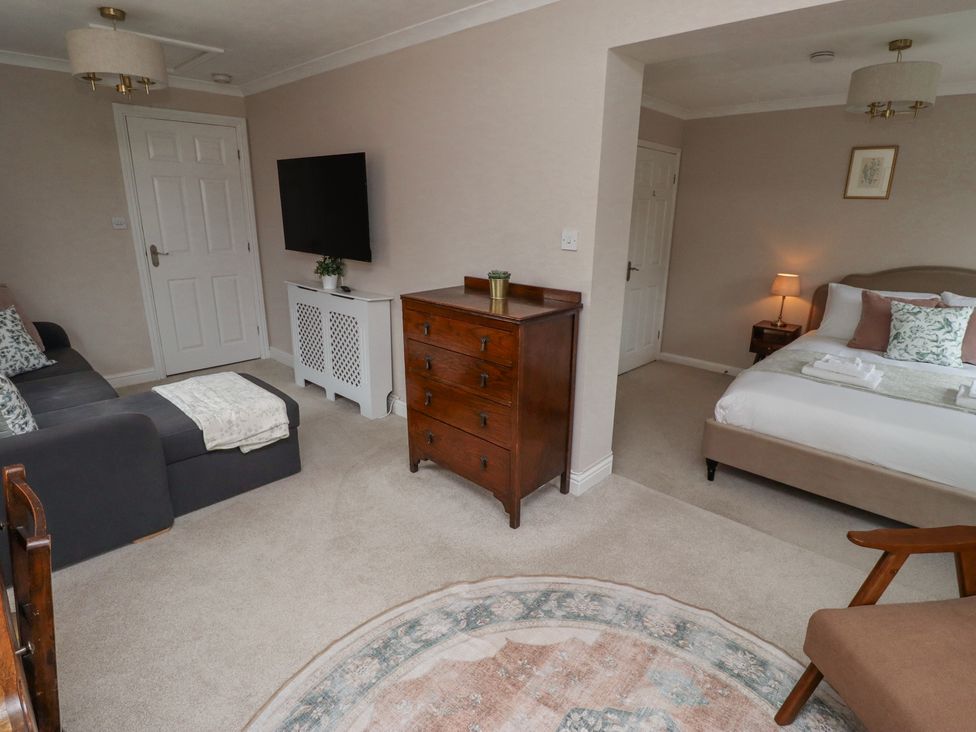 A room with a gray sofa and a wooden chest of drawers next to a bed with pillows at Sparrow House in Alnwick
