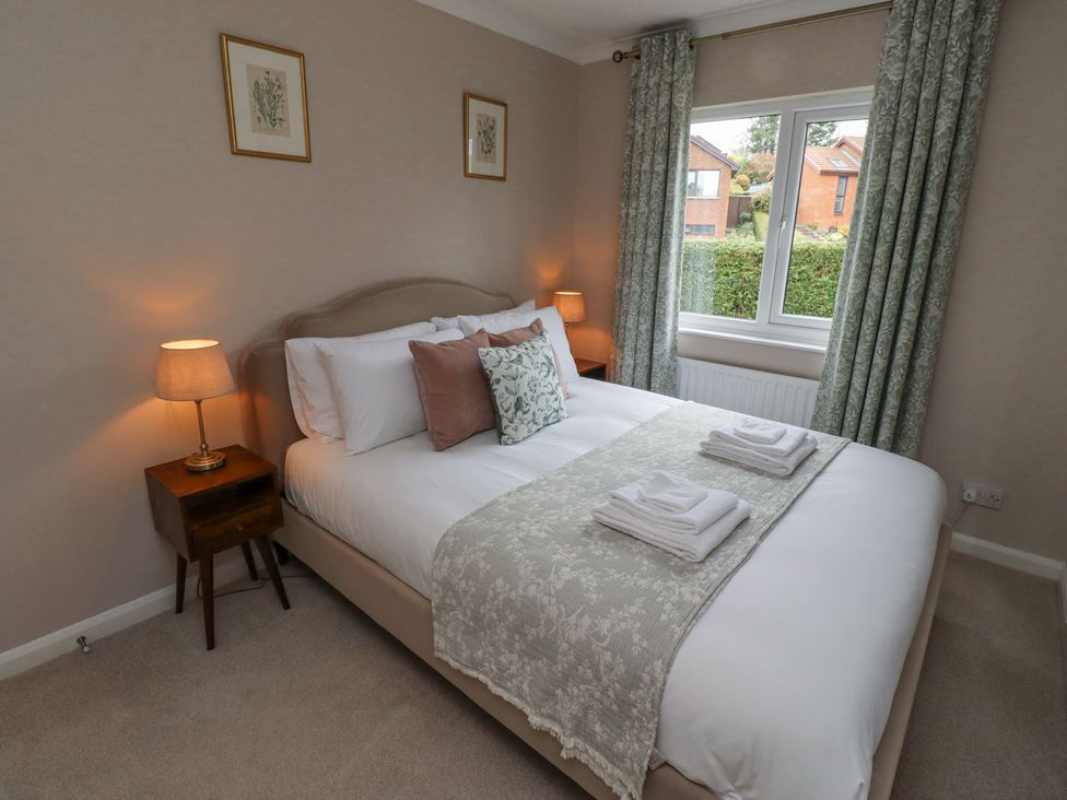 A bedroom with a bed with pillows and folded towels next to a window with curtains at Sparrow House in Alnwick