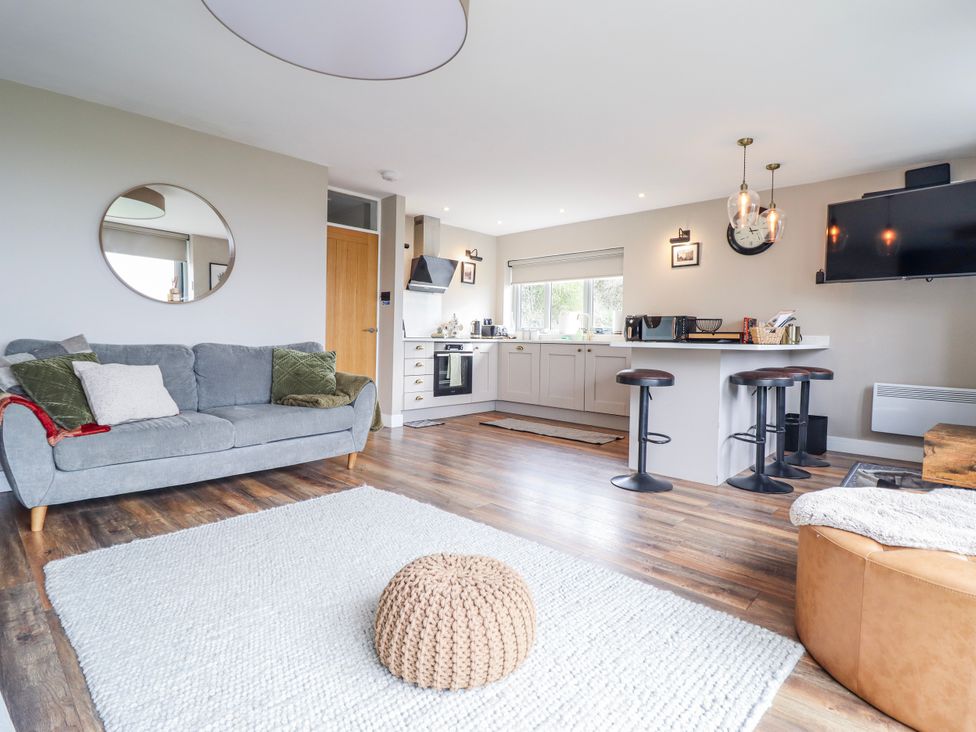 A living room with a kitchen area and a sofa at Hafod Y Bryn in Harlech