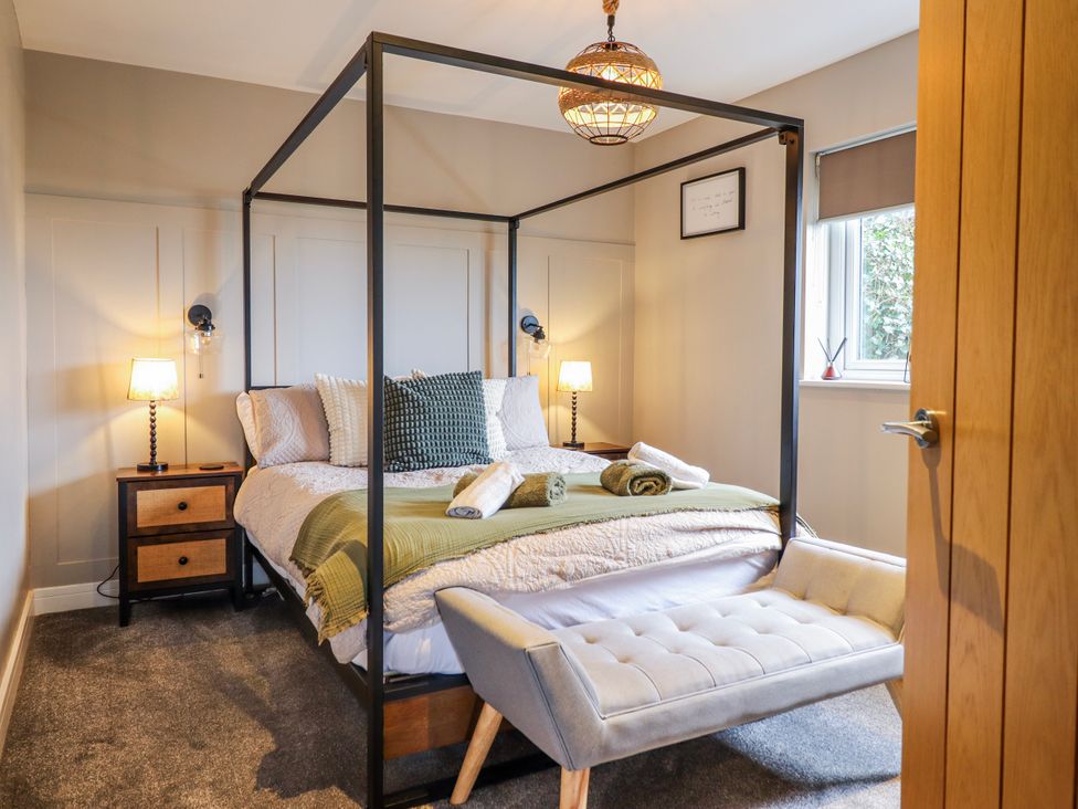 A bedroom with a four-poster bed and seating area at Hafod Y Bryn in Harlech
