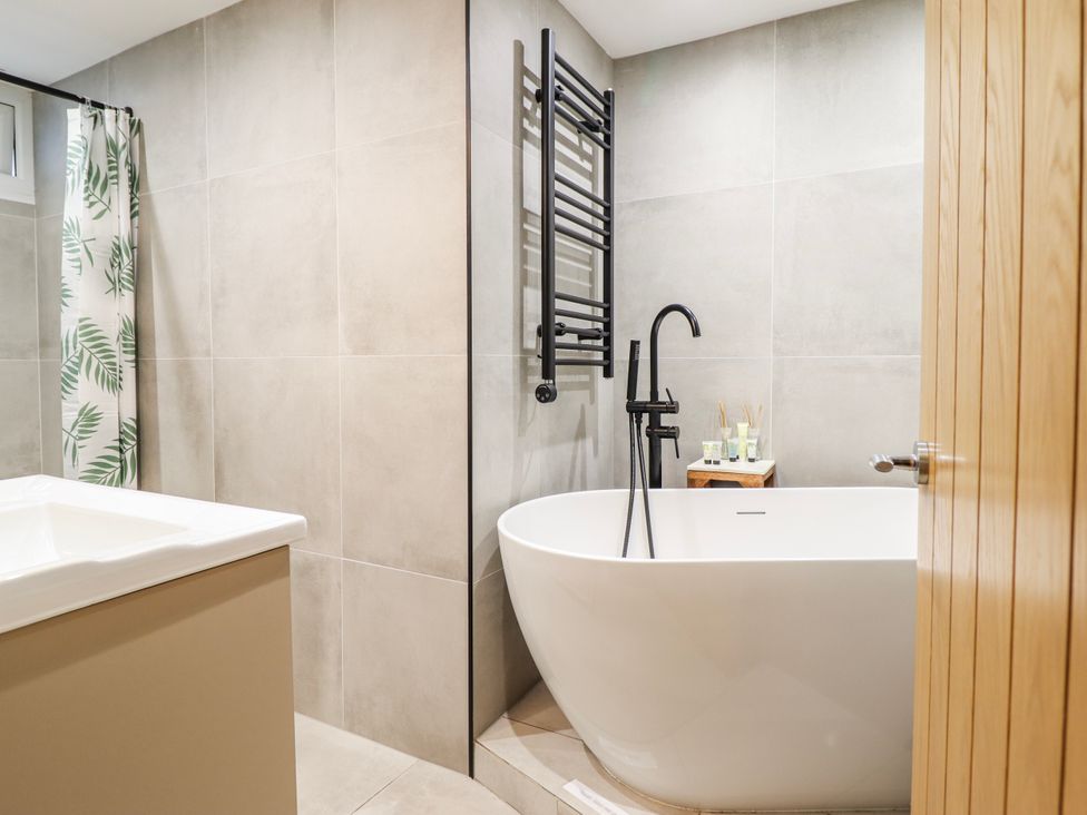 A bathroom with a bathtub and shower curtain at Hafod Y Bryn in Harlech