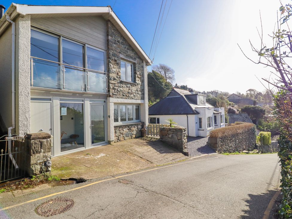 An exterior view of a house with windows and a stone wall at Hafod Y Bryn in Harlech