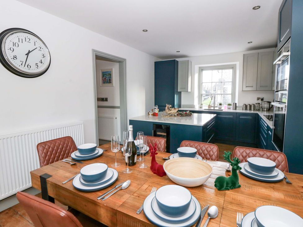 A dining room with a wooden table set for dinner at Island House Aberaeron