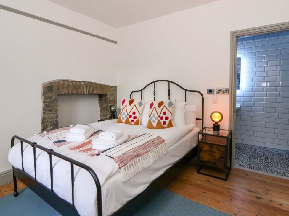 A bedroom with a bed and stone wall at Island House in Aberaeron