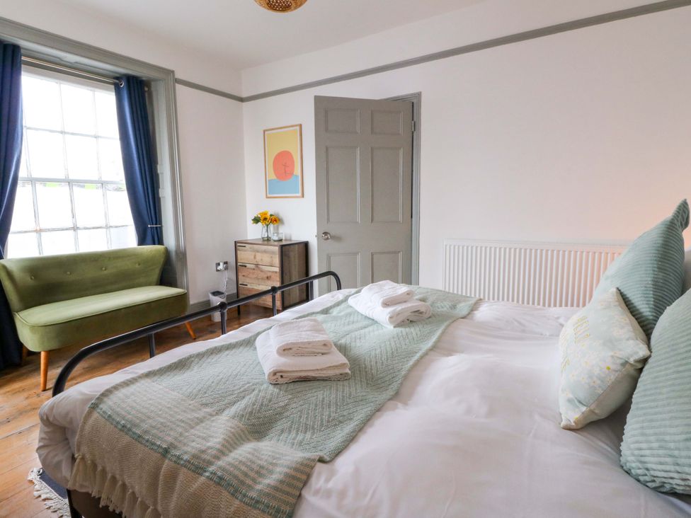 A bedroom with a bed and a green sofa at Island House in Aberaeron