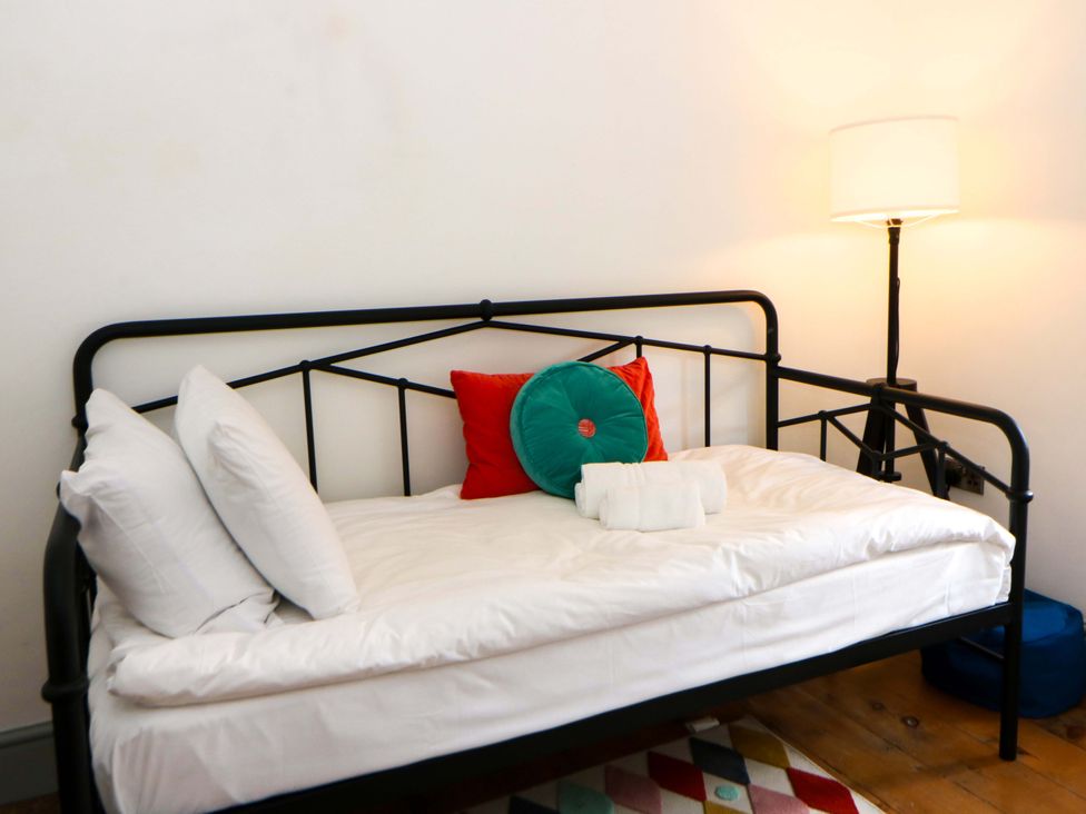 A bed with pillows and cushions in a bedroom at Island House in Aberaeron