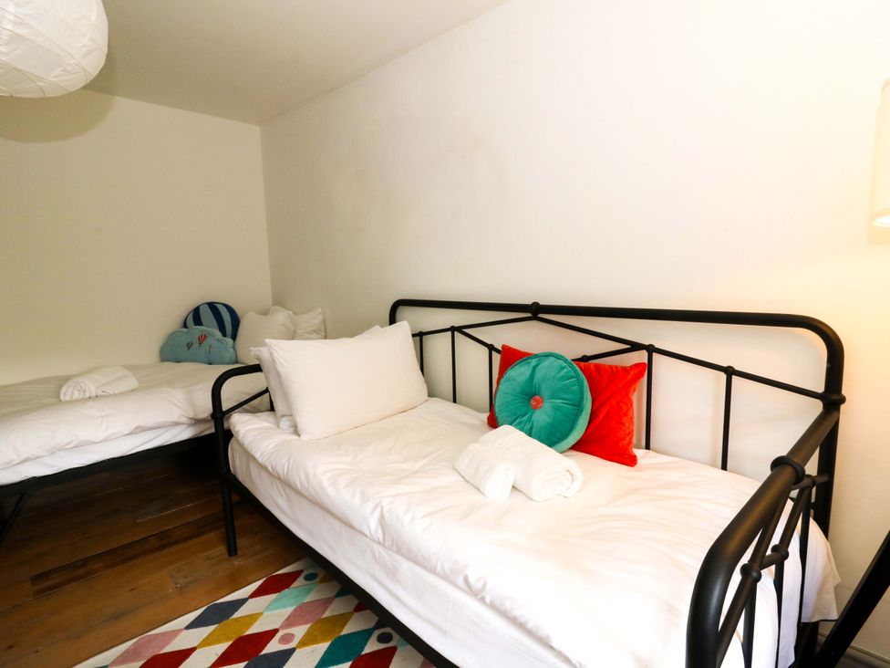 A bedroom with two beds and a rug at Island House Aberaeron