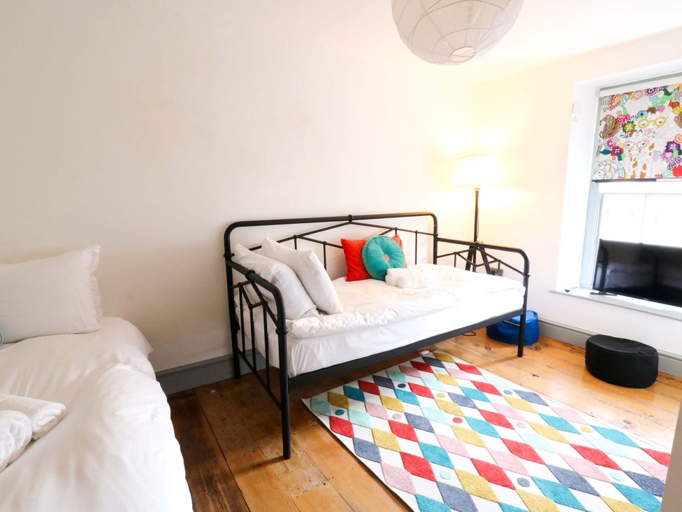 A bedroom with a metal bed, rug, lamp and window at Island House Aberaeron