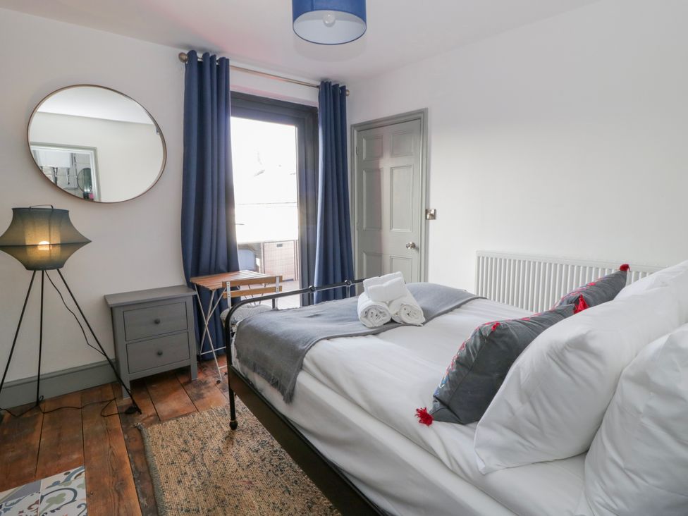 A bedroom with a bed, lamp, and mirror at Island House in Aberaeron