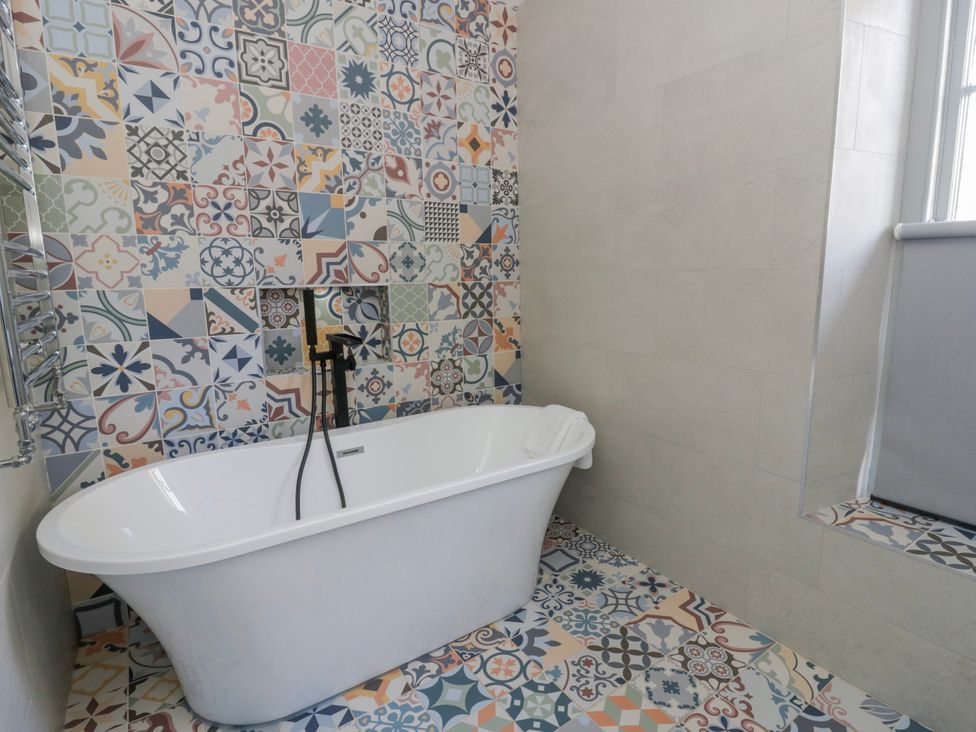 A bathroom with a bathtub and patterned tiles at Island House in Aberaeron