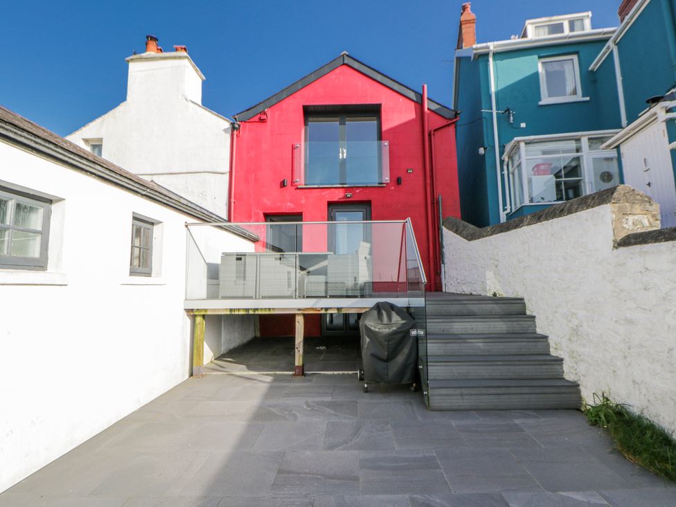 An outdoor area with a red house and deck at Island House Aberaeron