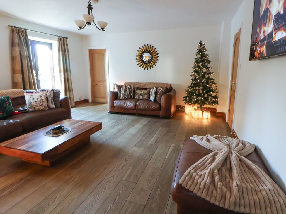 A living room with a Christmas tree and brown furniture at Brookway Lodge in Caerwys