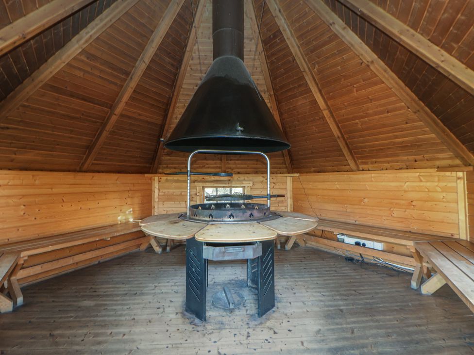 A circular table with a fireplace in a wooden room at Brookway Lodge Caerwys