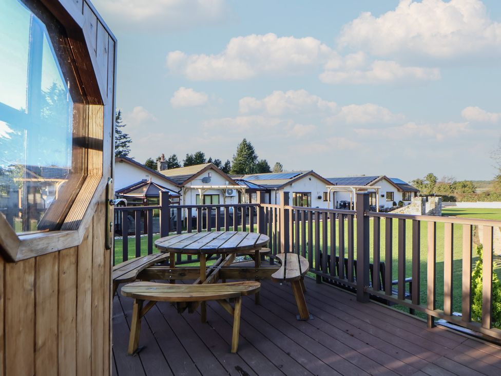 An outdoor deck with a table and chairs at Brookway Lodge in Caerwys