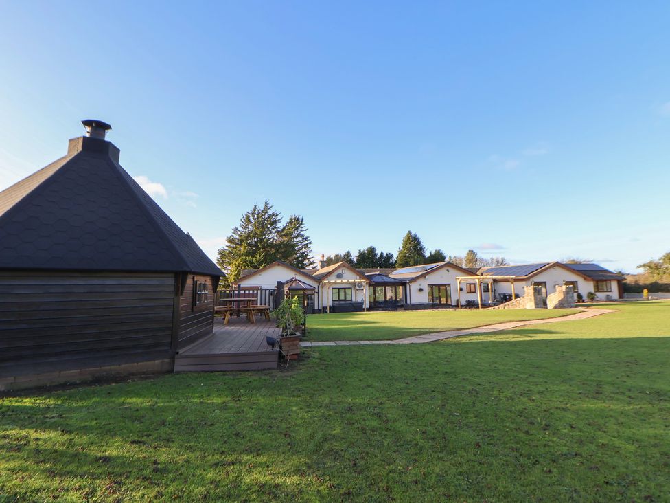 An outdoor area with multiple buildings and a wooden structure at Brookway Lodge in Caerwys