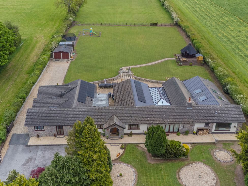 An aerial view of a house with a garden and playground at Brookway Lodge, Caerwys