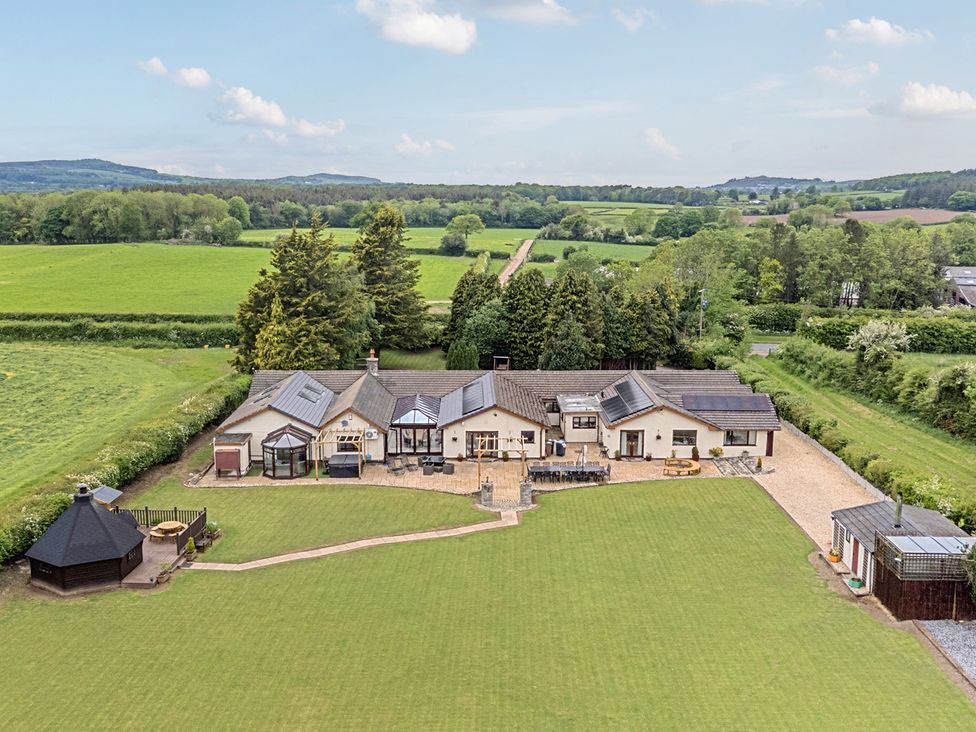 A garden with a house and patio area at Brookway Lodge in Caerwys