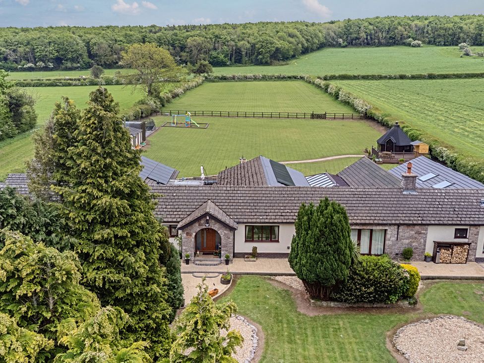 An outdoor view of a house with a garden and playground at Brookway Lodge Caerwys