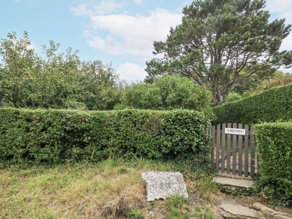 An entrance gate with a sign reading CHENIES surrounded by greenery at Chenies in Osmington Mills near Preston