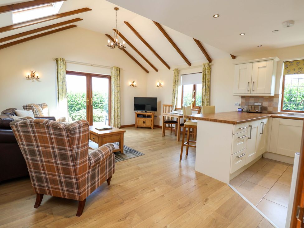 A living room with a sofa and dining area at The Brambles in Holt, North Wales