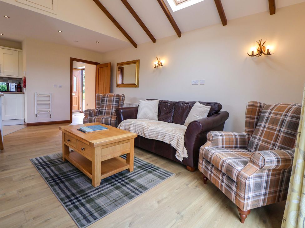 A living room with a sofa and armchairs at The Brambles in Holt, North Wales