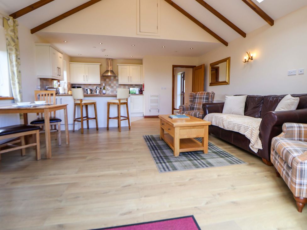 A living room with a sofa and table at The Brambles in Holt, North Wales